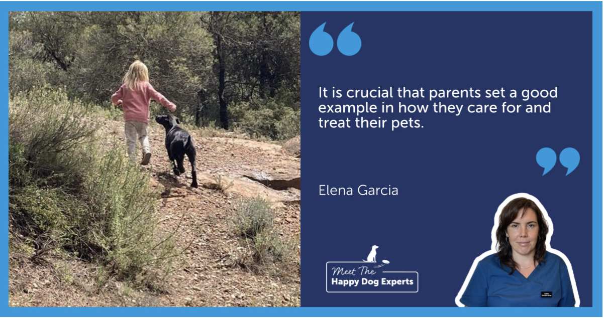 A black dog looking up at a child as they walk.